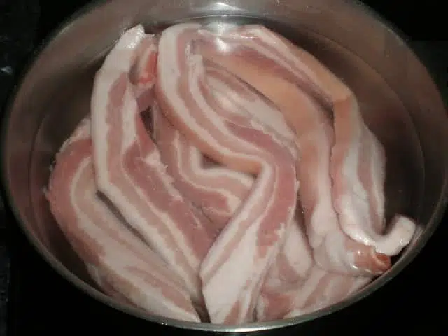 Tiras de panceta fresca en cazuela con agua y sal
