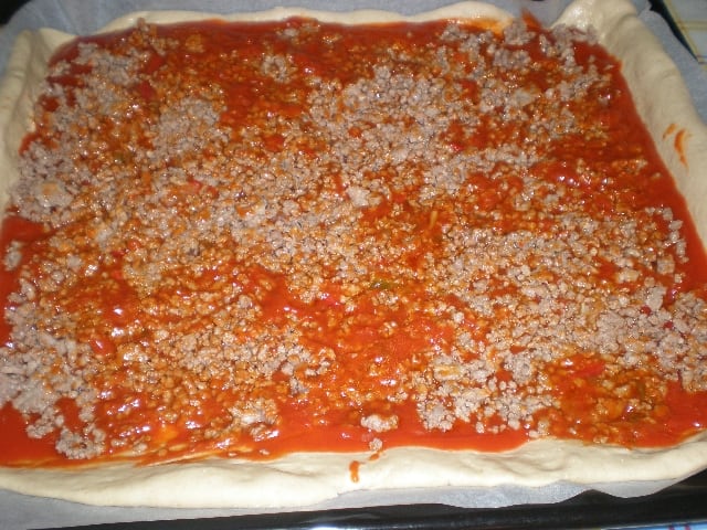 Masa de pizza con tomate y carne