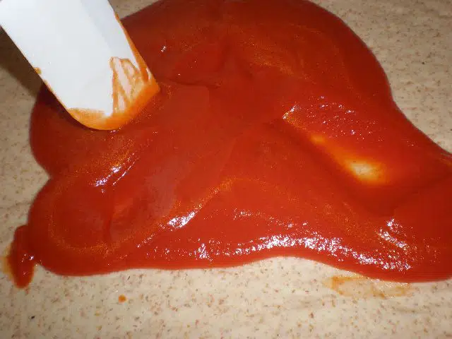 Poner el tomate en la masa de la pizza