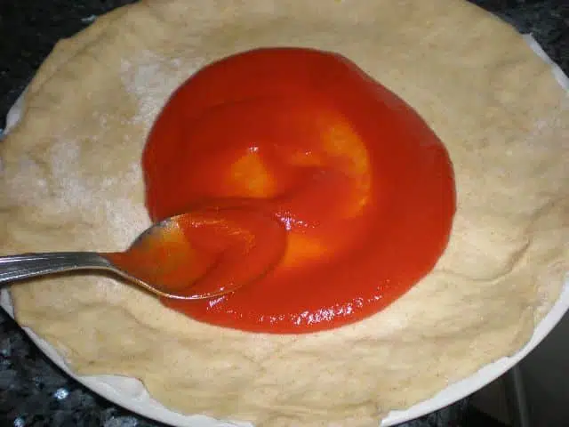 Poner tomate a la pizza